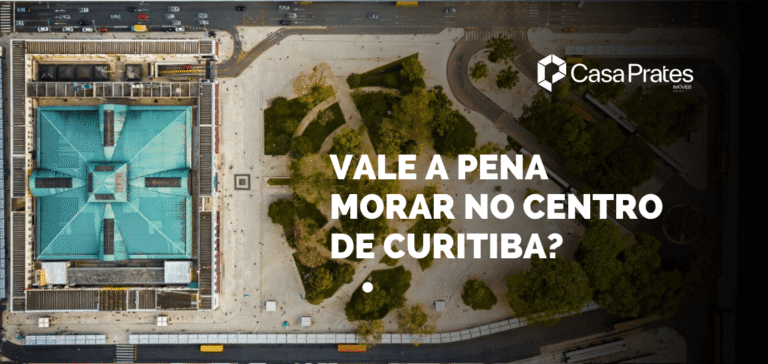 Vista aérea do centro de Curitiba com praça, vias urbanas e edifícios, destacando o texto “Vale a pena morar no centro de Curitiba?” e a marca Casa Prates Imóveis.