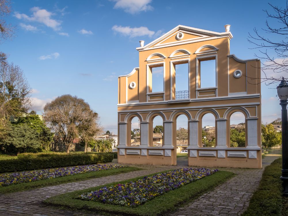 Ruínas de São Francisco em meio a jardim florido, representando história, cultura e áreas verdes que contribuem para a qualidade de vida em Curitiba.