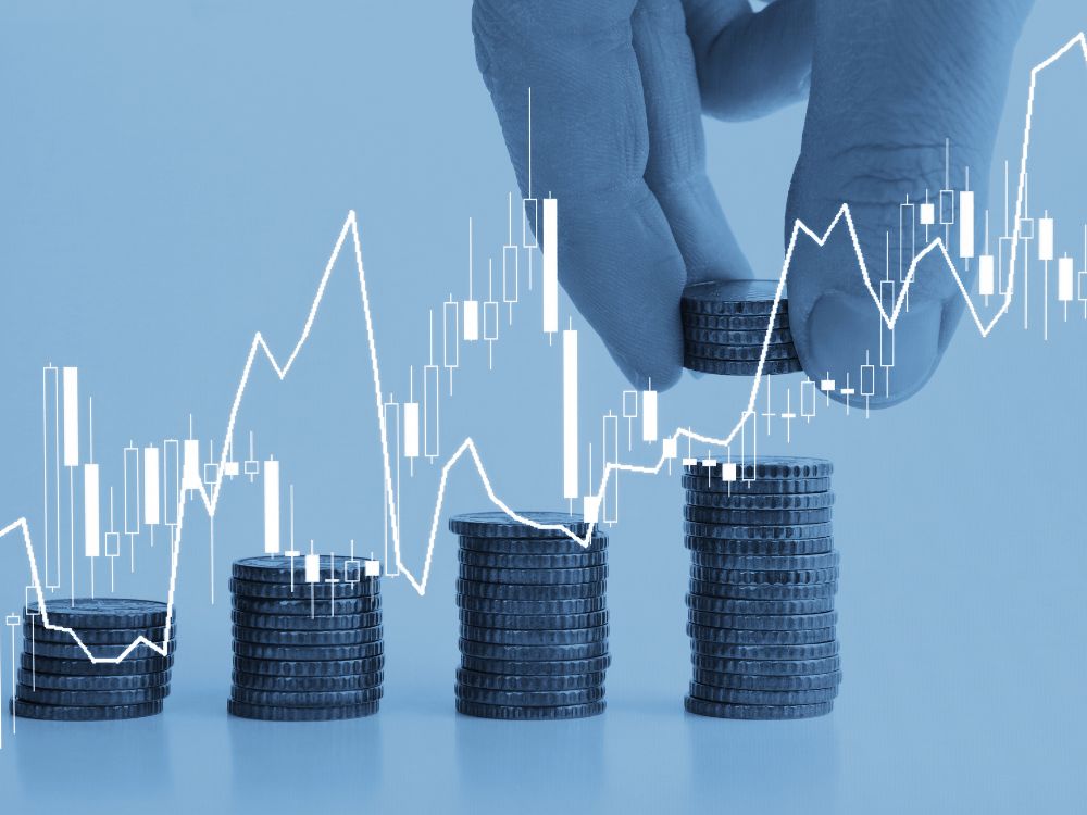 Pilhas de moedas sobre gráfico de mercado, com linha de crescimento em destaque, representando alta nos lucros com aluguéis.