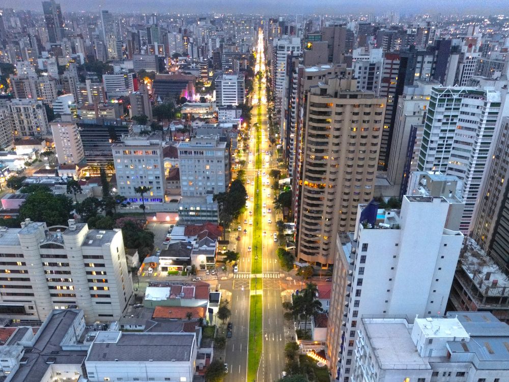 Avenida iluminada em Curitiba à noite, mostrando o movimento urbano e como morar em Curitiba une praticidade, segurança e mobilidade urbana.
