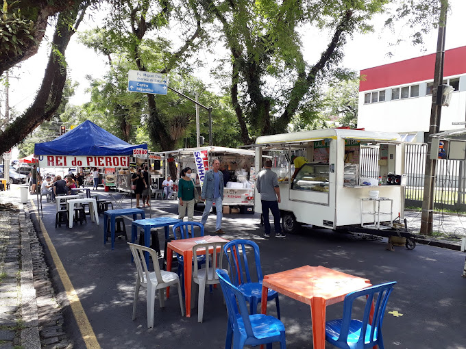 Feira do Batel em Curitiba com barracas e mesas coloridas, oferecendo culinária internacional e ambiente descontraído. O que é feira do Batel?
