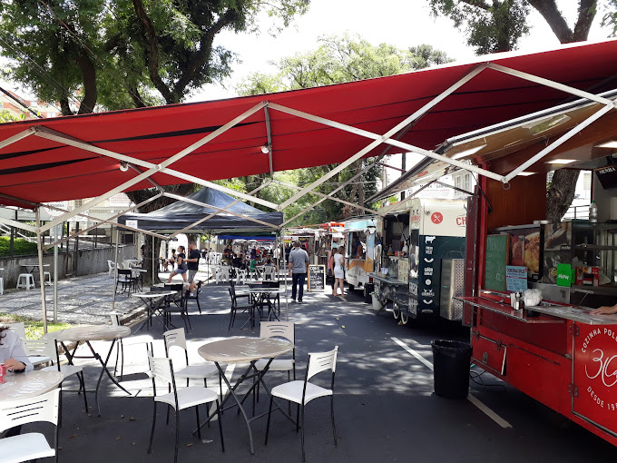 Barracas e mesas dispostas ao longo de rua na Feira do Batel, um evento gastronômico imperdível em Curitiba. O que é feira do Batel?
