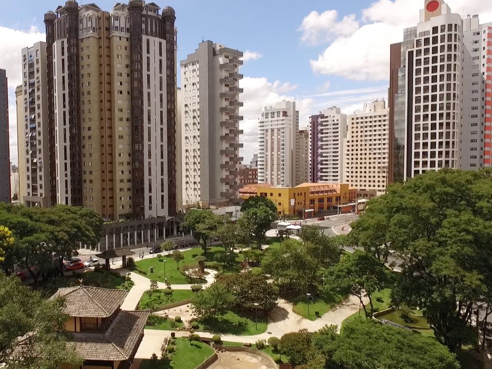 Praça do Japão, localizada no bairro Batel em Curitiba, com jardins tradicionais cercados por edifícios sofisticados.