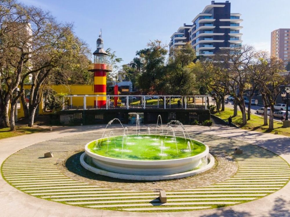 Praça com chafariz e farol em Curitiba, destacando a infraestrutura e áreas de lazer que influenciam o custo de vida em Curitiba.