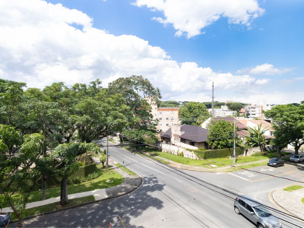 Rua tranquila no Bairro Água Verde Curitiba, com árvores e casas residenciais, ideal para quem busca saber se o bairro Água Verde Curitiba é bom.