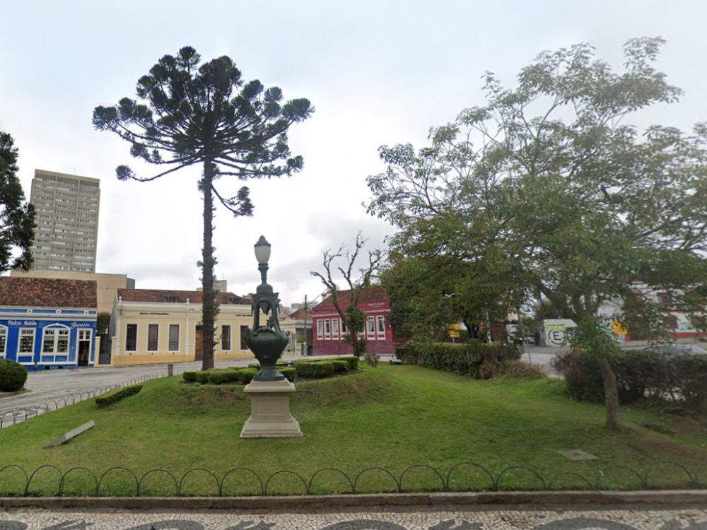 Praça arborizada com casarões coloridos ao fundo no setor histórico de Curitiba, destacando o charme e o valor cultural da região central.