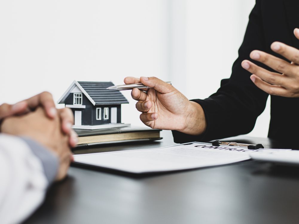 Consultoria imobiliária com maquete de casa e contrato, reforçando o planejamento necessário para investir em Curitiba com foco em aluguel.