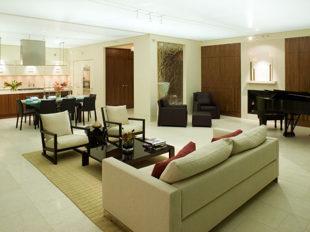 Sala de estar ampla e sofisticada, com design contemporâneo e integração com a cozinha e sala de jantar, tendência de imóveis de luxo em 2025.