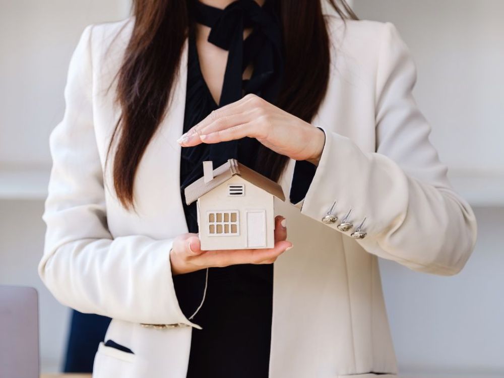 Mulher segurando miniatura de casa, simbolizando segurança patrimonial e como calcular rentabilidade de aluguel antes de investir em imóveis.