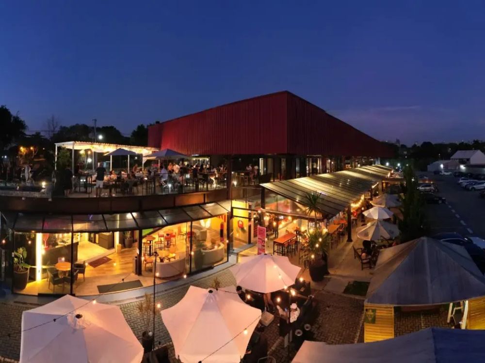 Vista noturna de um restaurante em Curitiba, com mesas ao ar livre e ambiente iluminado, perfeito para um passeio em família.