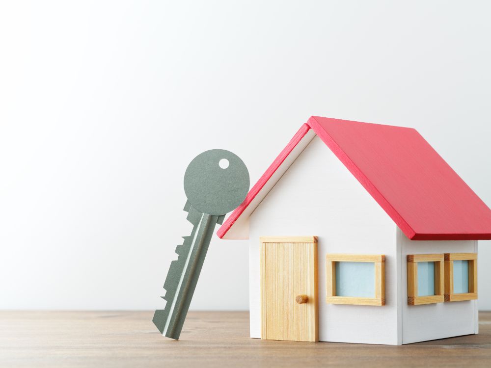 Chave apoiada sobre casa em miniatura representando como funciona o título de capitalização para aluguel