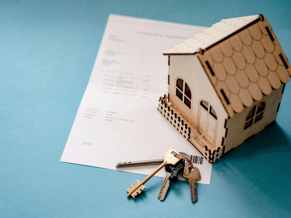 Modelo de casa sobre contrato com chaves simbolizando como funciona o título de capitalização para aluguel