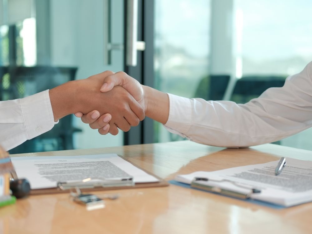 Aperto de mãos após negociação imobiliária, simbolizando acordo baseado nos Índices de reajuste de aluguel previstos em contrato.