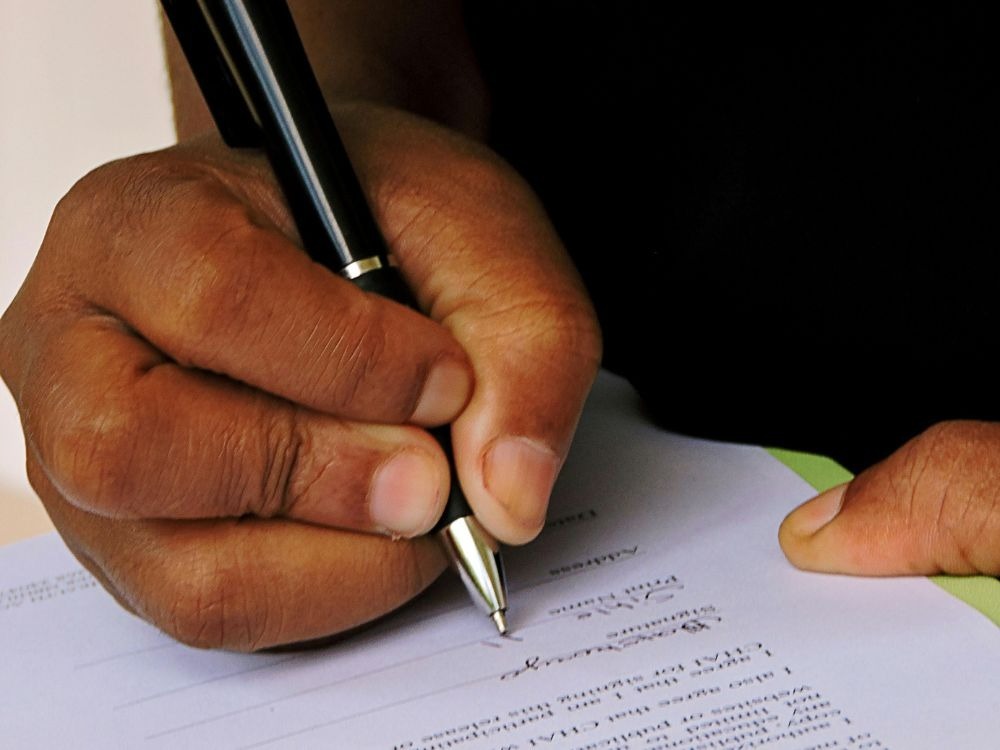 Close em mão assinando contrato de aluguel com foco nos Índices de reajuste de aluguel estabelecidos na locação.