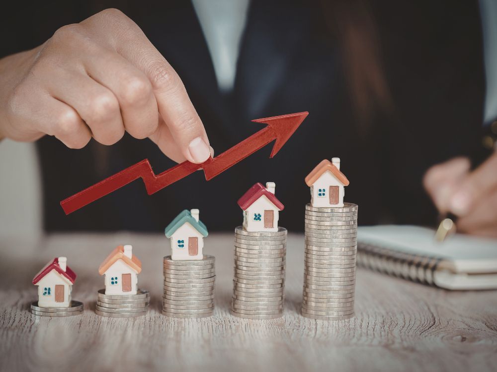 Valorização de imóveis representada por casas sobre moedas e gráfico de crescimento, cenário que ilustra o que faz a imobiliaria no mercado imobiliário