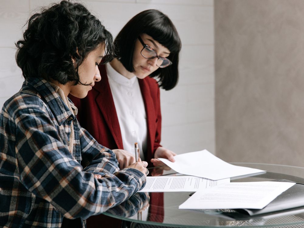 Cliente assinando contrato com corretor analisando se vale a pena colocar imóvel na imobiliária