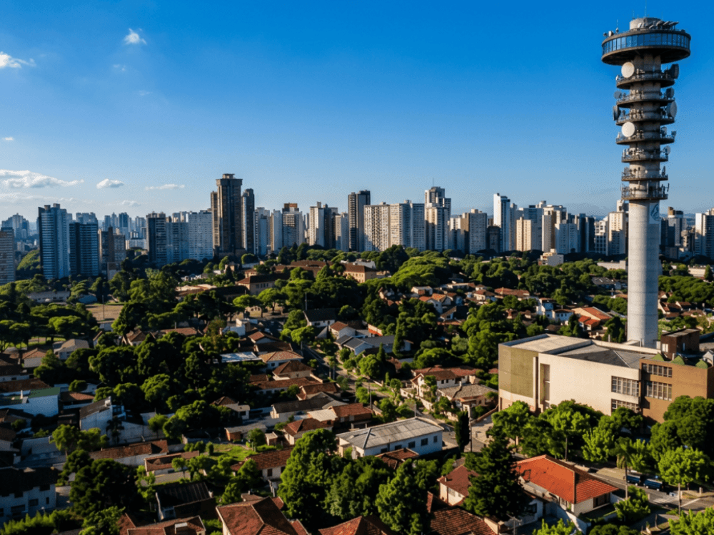 Vista do bairro Mercês com torre de telecomunicações, áreas residenciais e edifícios ao fundo em Curitiba.