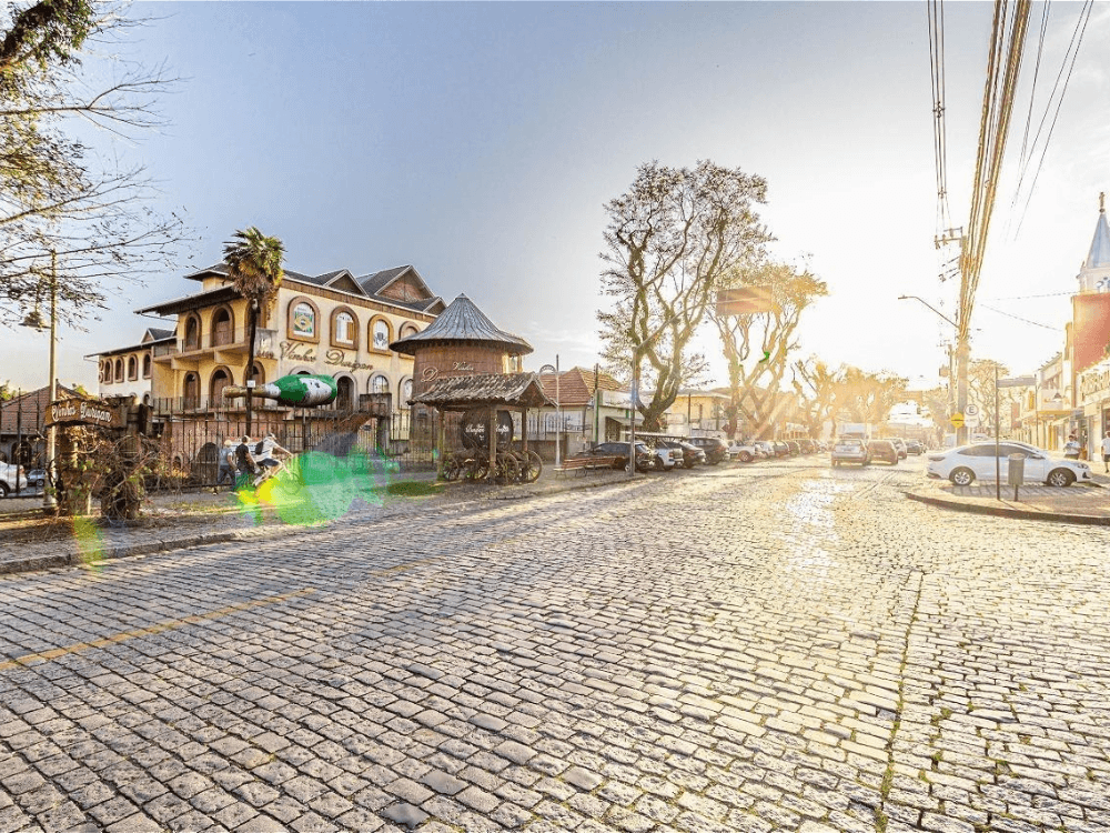 Rua de paralelepípedos com construções tradicionais e comércio no bairro Santa Felicidade em Curitiba.