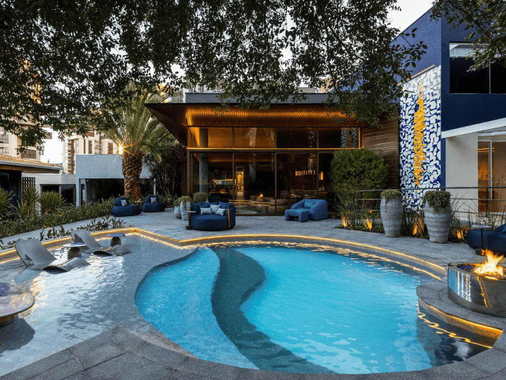 Ambiente externo sofisticado com piscina iluminada e arquitetura contemporânea apresentado na CASACOR 2026 no Paraná.