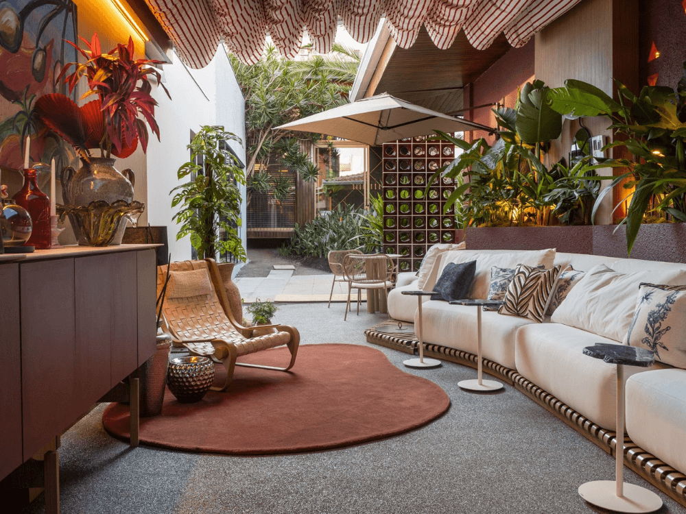 Sala de estar elegante com vegetação abundante e integração entre áreas internas e externas na CASACOR Paraná.